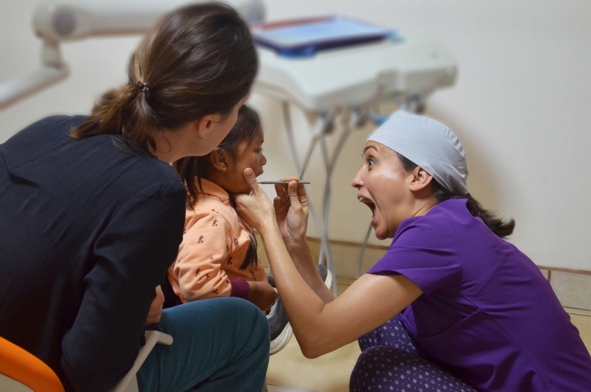 Dentist treating a child patient and making a funny grimace